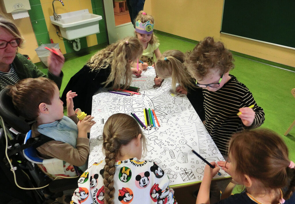 Kinder und Erwachsene arbeiten an einem gro&szlig;en Malbild