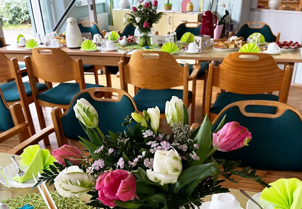 Frühlingshafte Tischdekoration mit Blumen in einem Gemeinschaftsraum