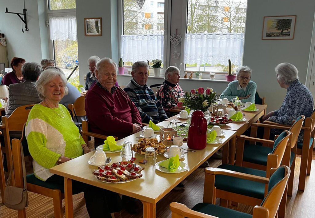 &Auml;ltere Menschen sitzen gemeinsam an einem Tisch und genie&szlig;en eine gesellige Runde.