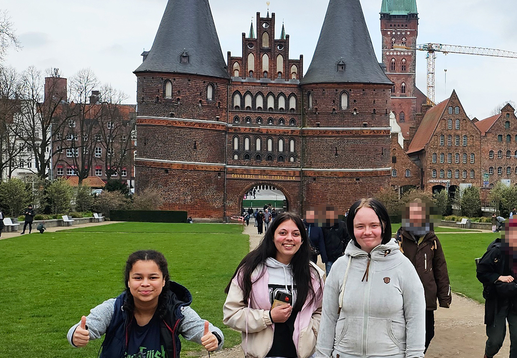 Drei Personen vor dem Holstentor in Lübeck, Deutschland.