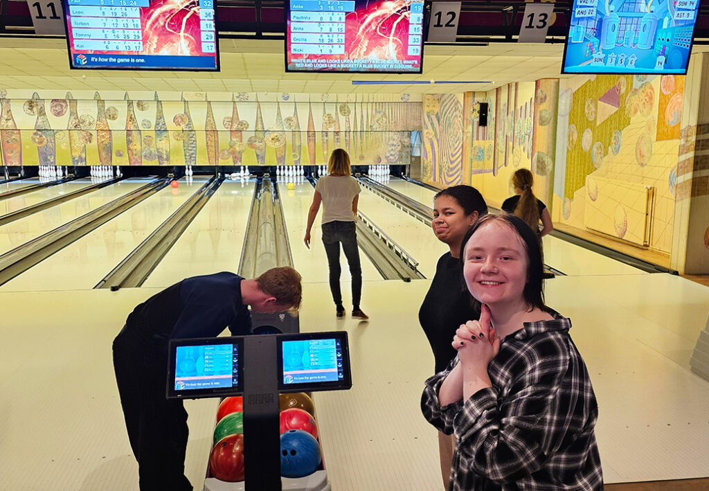 Gruppe von Menschen beim Bowling in einer Halle.
