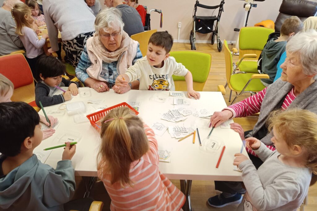 Kinder und Senioren bei einer Bastelaktivit&auml;t an einem Tisch