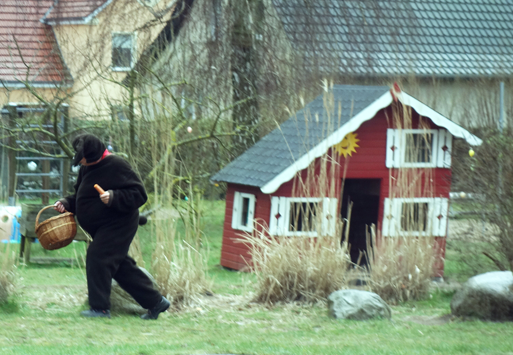 Person in Bärenkostüm mit Korb spaziert im Garten
