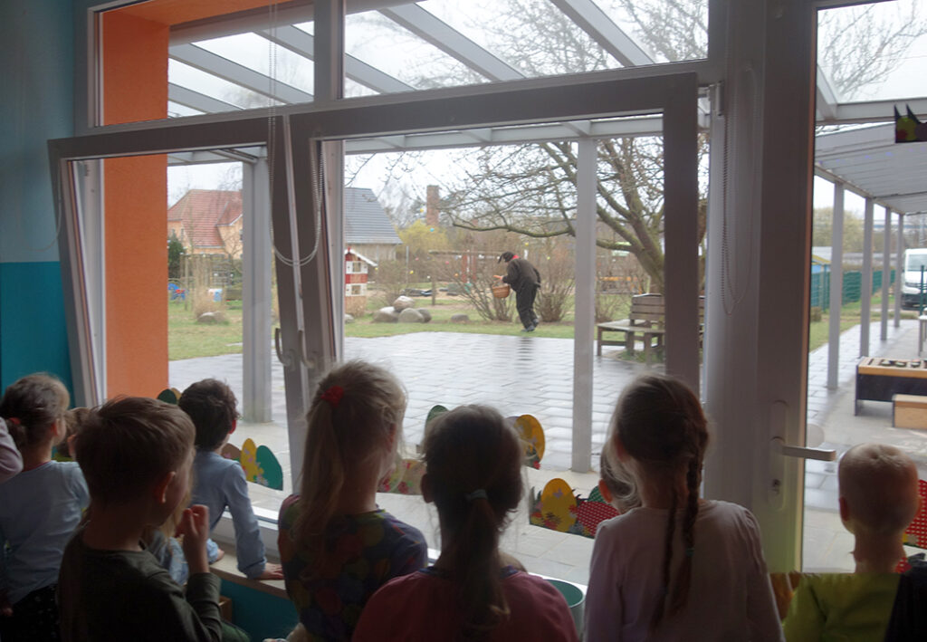 Kinder beobachten einen Mann drau&szlig;en durch ein Fenster