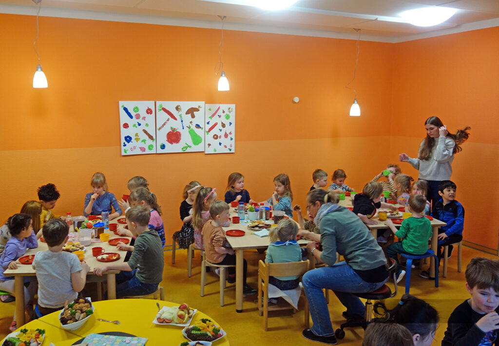 Gruppe von Kindern, die in einem Raum an Tischen sitzen