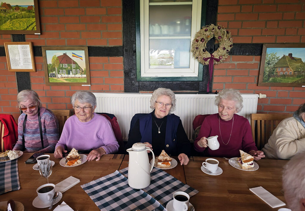 Eine Gruppe &auml;lterer Frauen sitzt an einem Tisch und genie&szlig;t Kaffee und Kuchen.