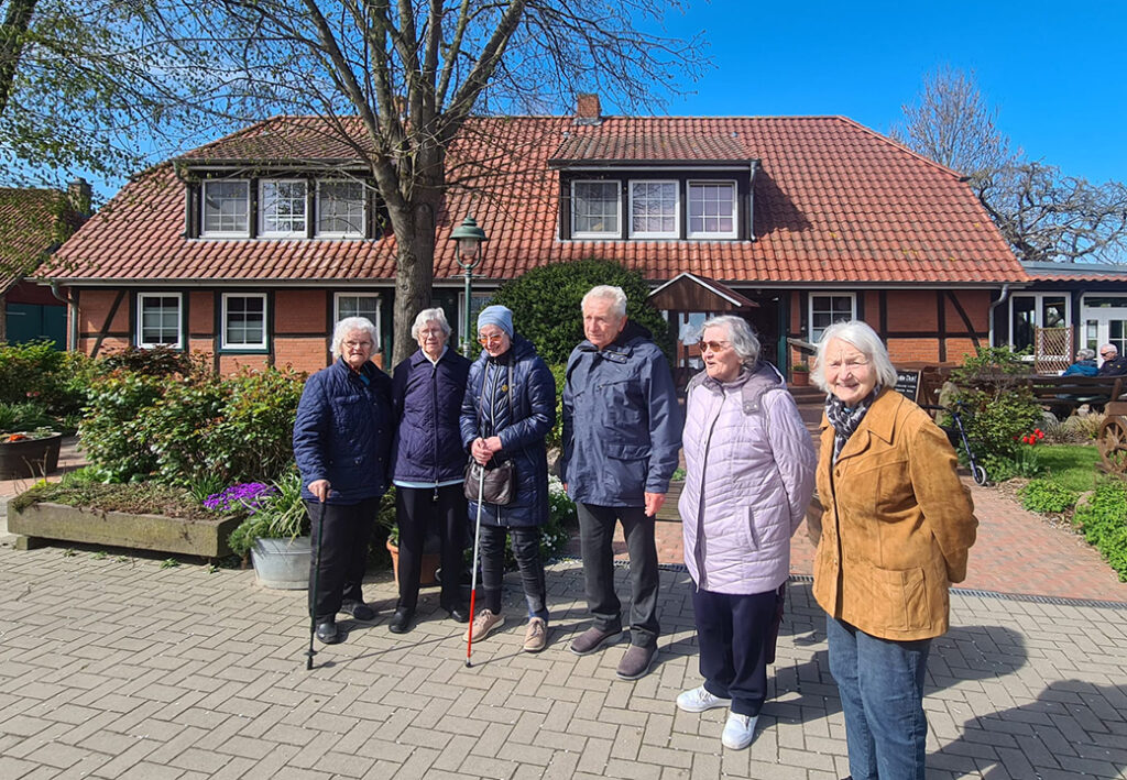 Senioren stehen vor einem Backsteinhaus