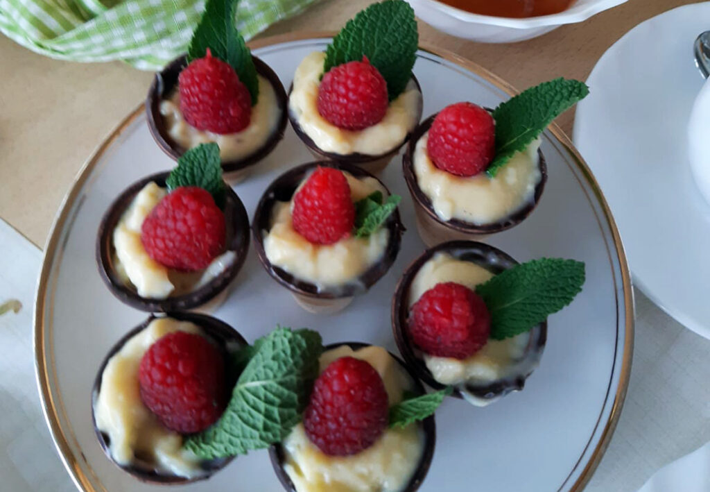 Kleine Dessertbecher mit Creme, Himbeere und Minzblatt