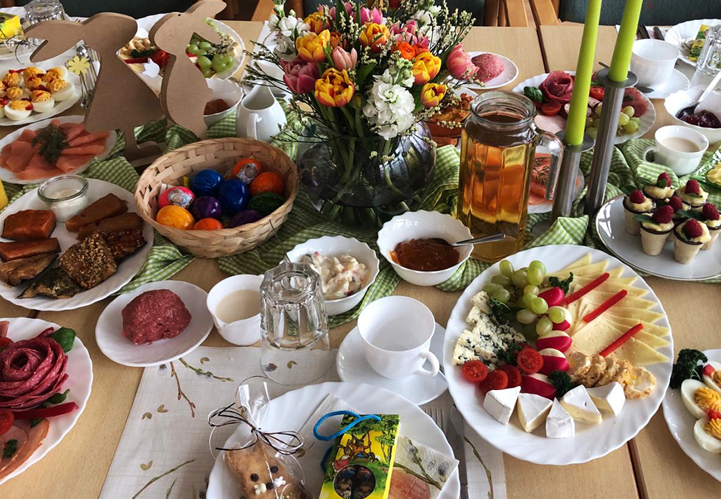 Reichlich gedeckter Tisch mit verschiedenen Speisen, Dekorationen und Blumen.