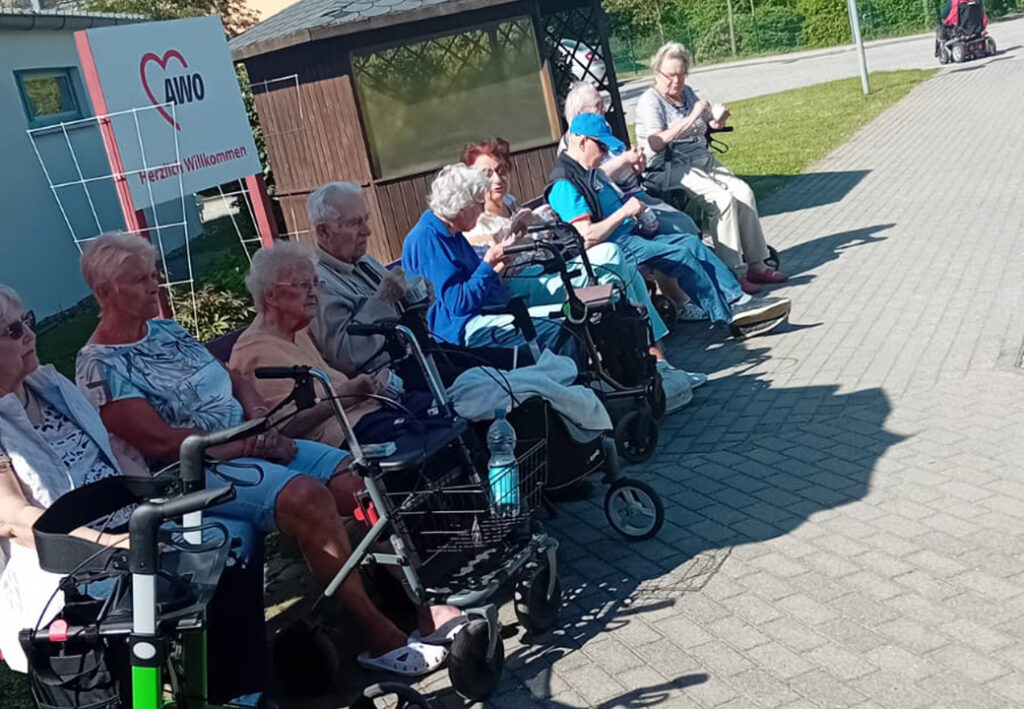 Gruppe von &Auml;lteren mit Rollatoren vor einem AWO-Geb&auml;ude