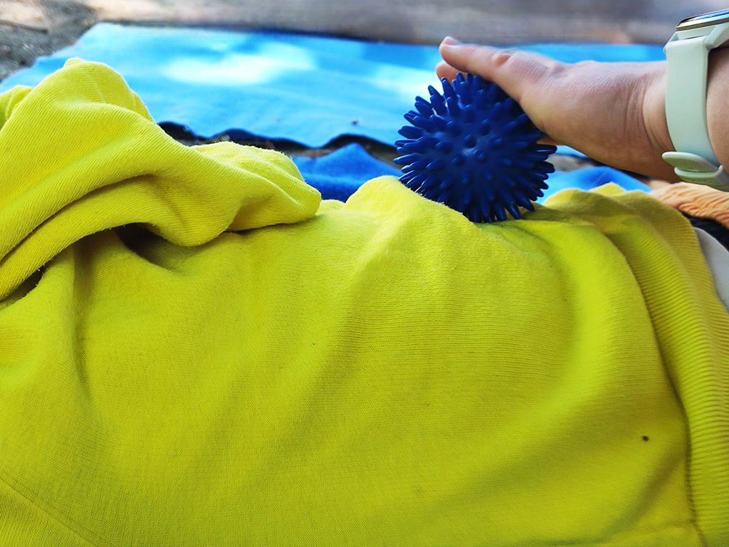 Person verwendet blauen Noppenball auf gelbem Stoff