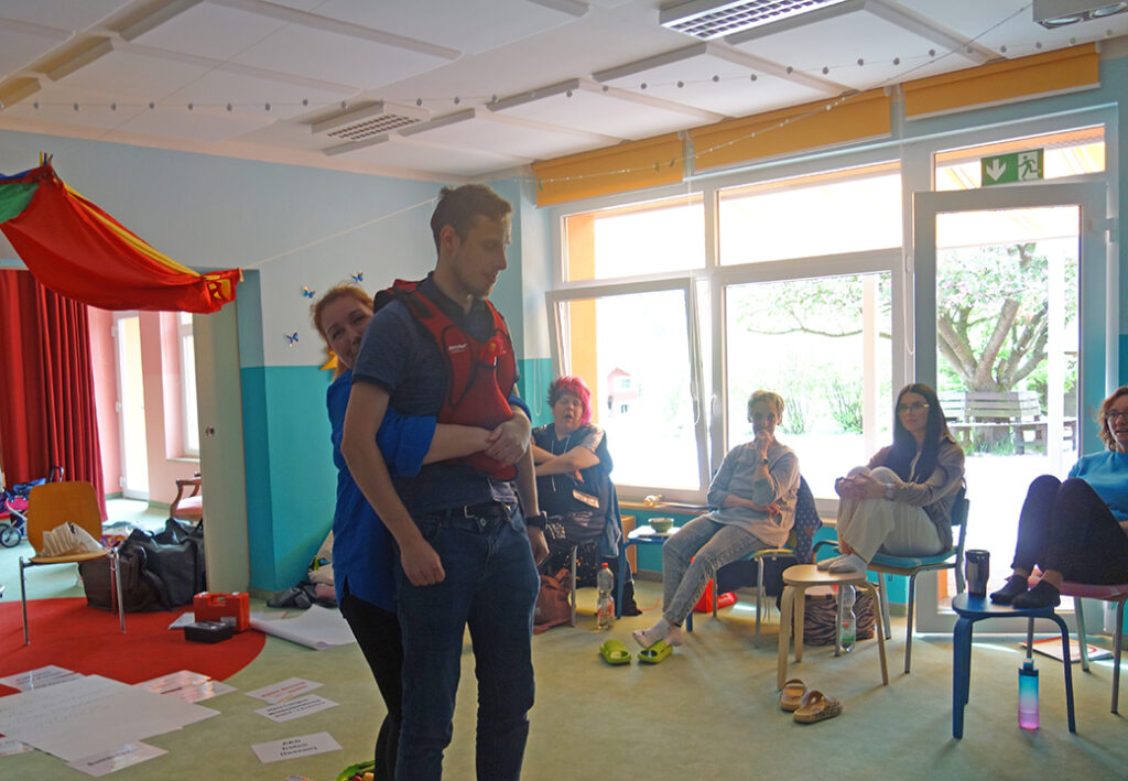 Personen in einem Gemeinschaftsraum w&auml;hrend einer Schulung oder &Uuml;bung.