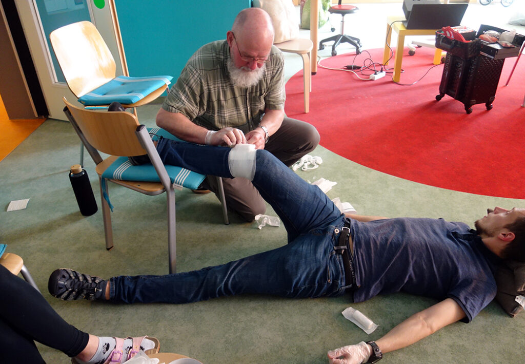 Ein Mann, der einem anderen Mann eine Bandage am Bein anlegt.