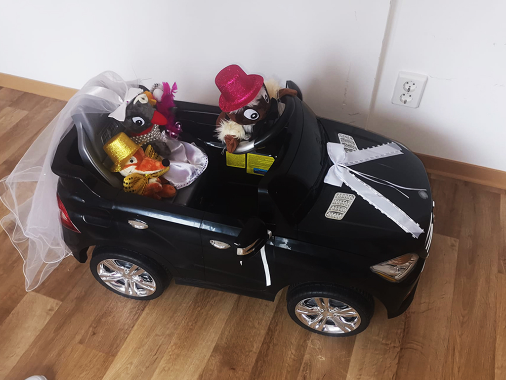 Ein Spielzeugauto mit ausgestopften Tieren in festlichen Hüten