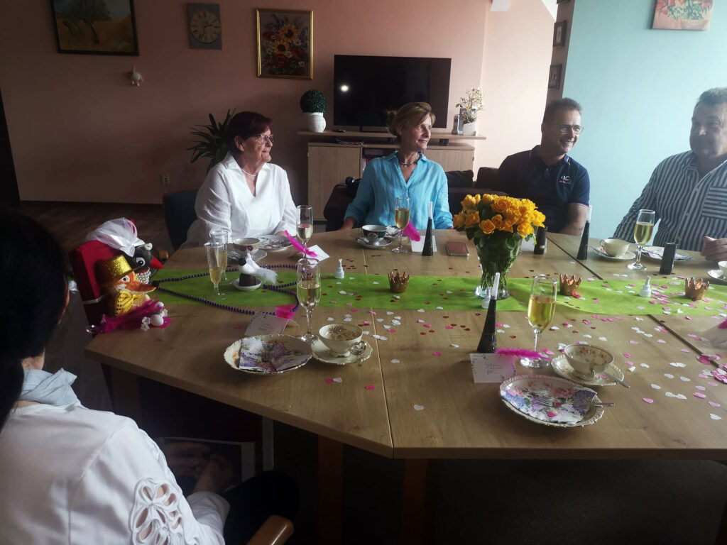 Menschen sitzen an einem festlich gedeckten Tisch und unterhalten sich.