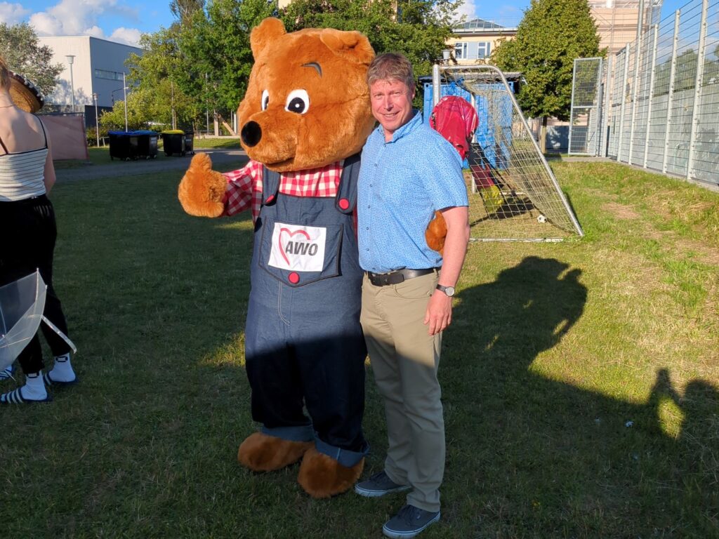 Ein Mensch steht neben einem gro&szlig;en B&auml;renkost&uuml;m w&auml;hrend einer Outdoor-Veranstaltung.