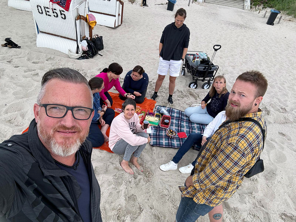 Menschen am Strand mit Picknickdecke