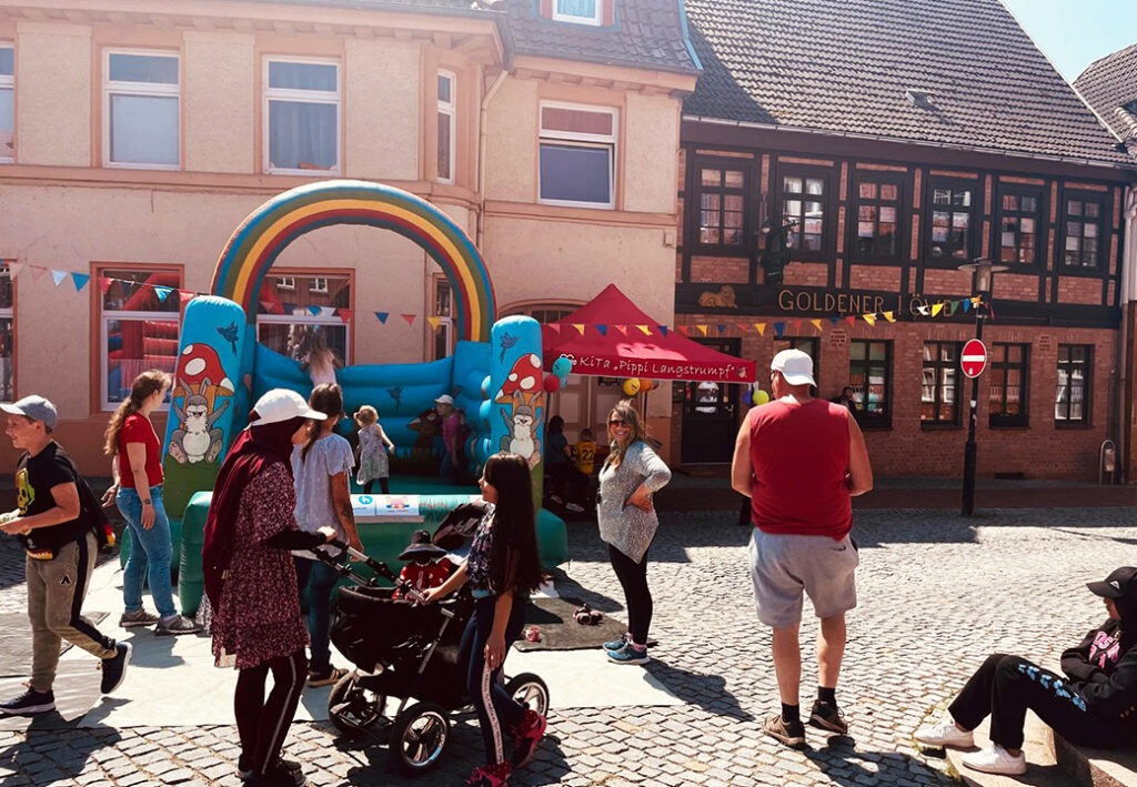 Menschen auf einem Straßenfest vor einer Hüpfburg und einem Zelt