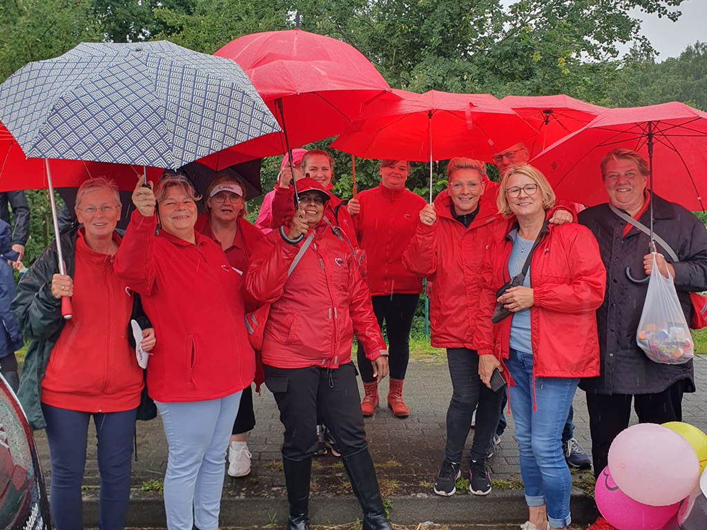 Menschen in roten Jacken mit roten Regenschirmen