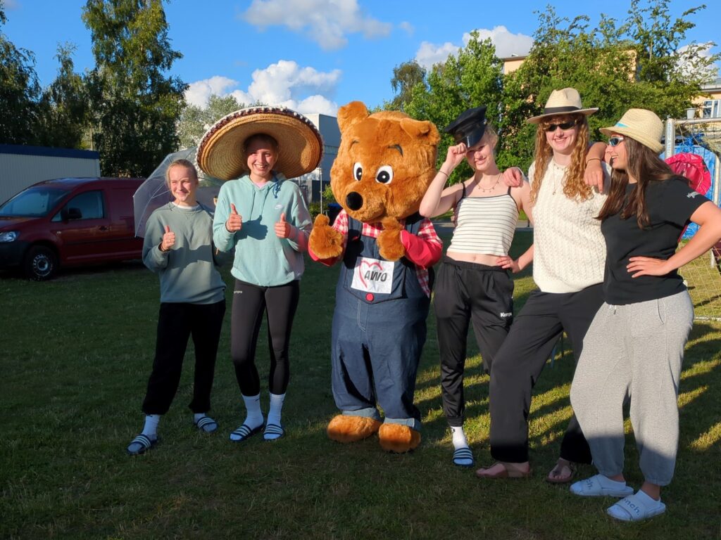 Gruppe von Menschen posiert mit einem B&auml;renkost&uuml;m im Freien