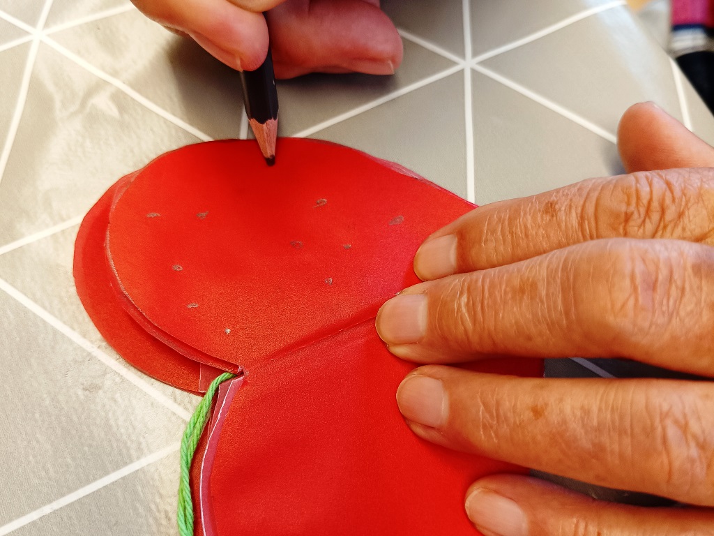 Person zeichnet auf rotes Filzmaterial