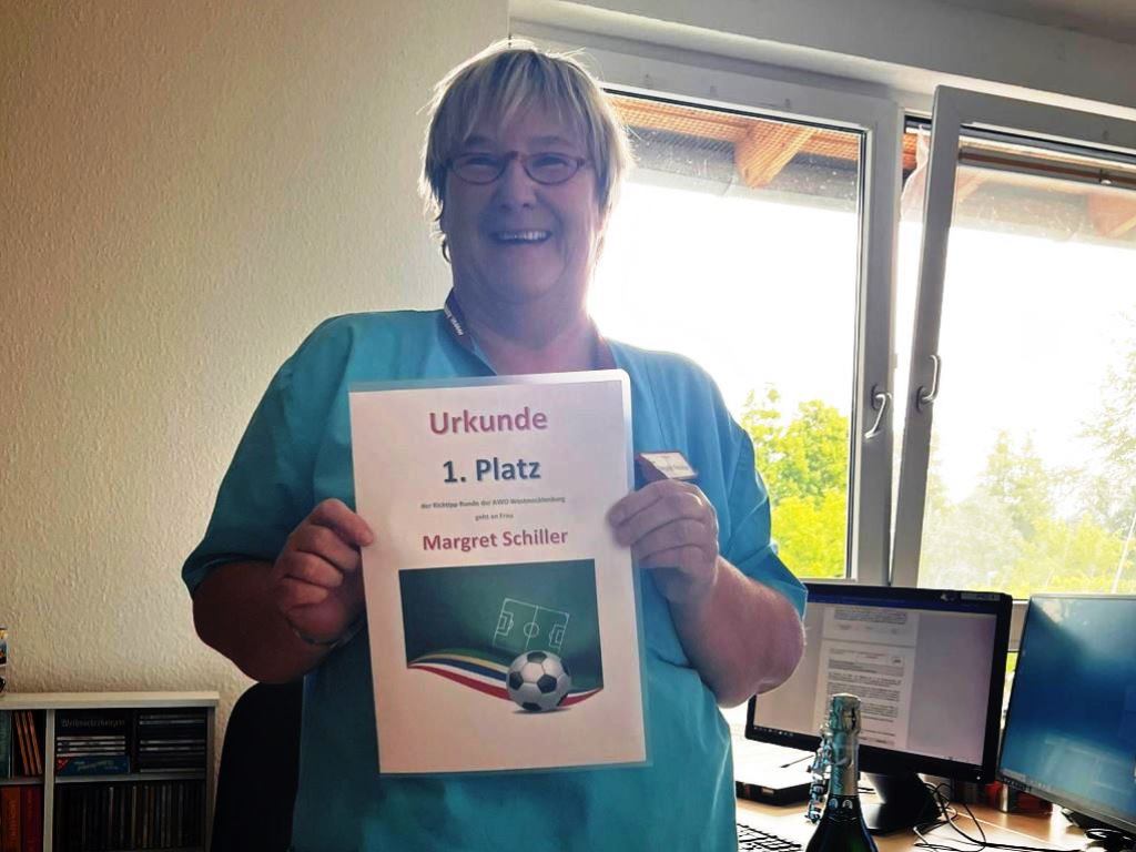 Eine Person hält eine Urkunde in die Kamera.