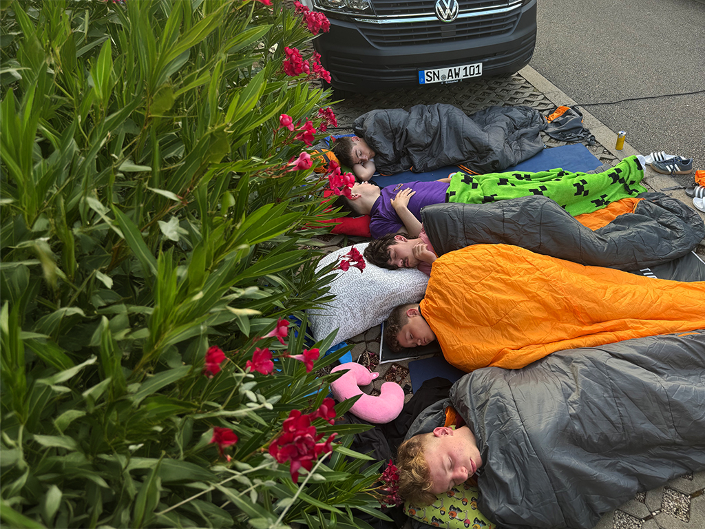 Gruppe von Personen in Schlafsäcken neben einem Fahrzeug