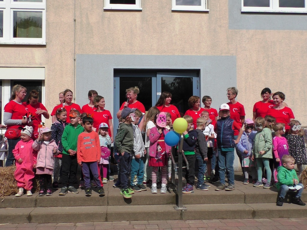 Gruppe von Kindern und Erwachsenen vor einem Gebäude