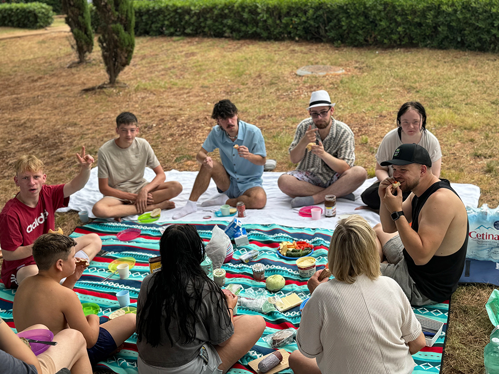 Gruppe von Menschen beim Picknick im Freien sitzend.