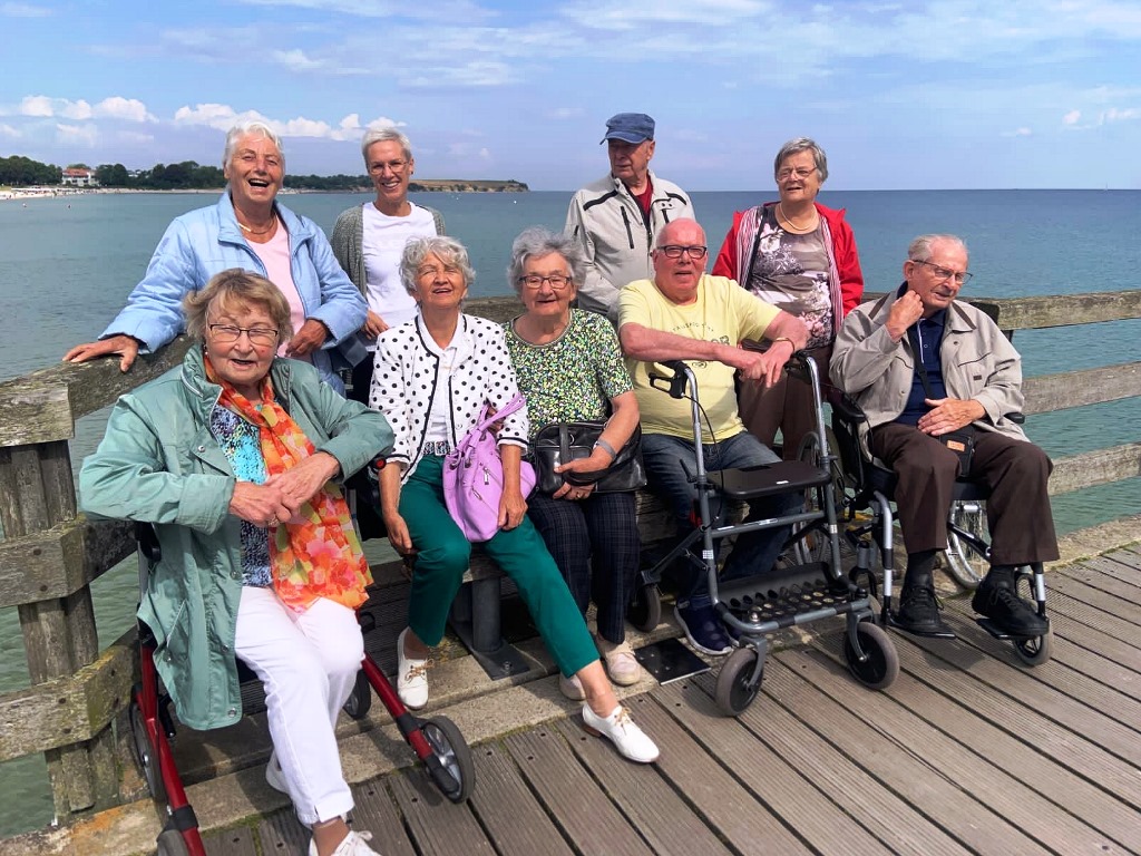 Gruppe von Senioren auf einem Pier mit Rollatoren und Rollstühlen