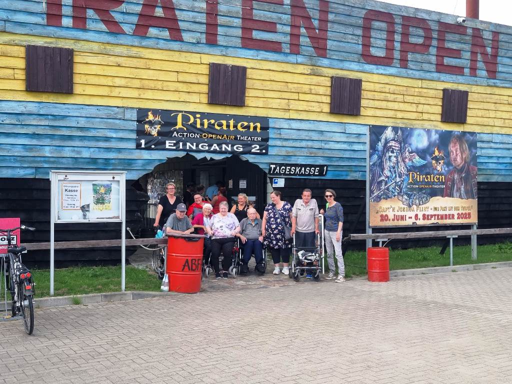 Eine Gruppe von Menschen steht vor einem Gebäude mit der Aufschrift 'Piraten Open'.