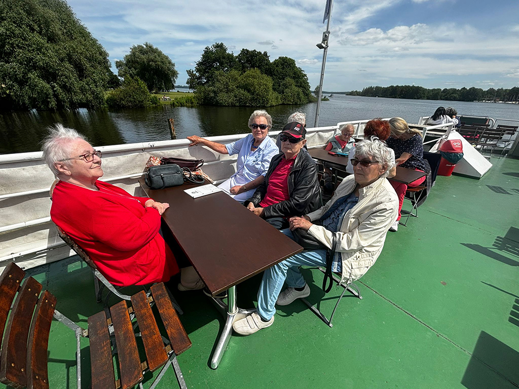 Eine Gruppe älterer Menschen sitzt an einem Tisch auf einem Schiff.