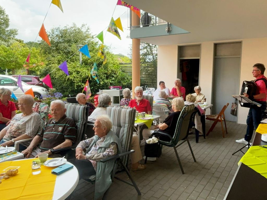 Menschen bei einer Feier mit bunten Wimpeln und Akkordeonspieler
