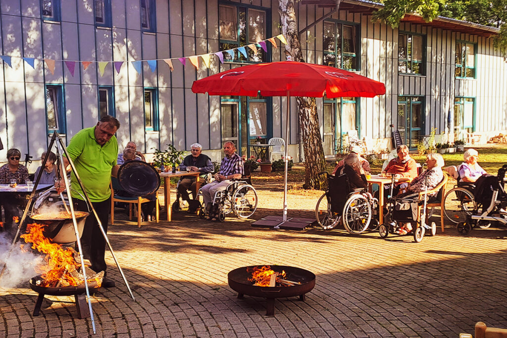 Gruppe von Menschen bei einem Fest im Freien mit Lagerfeuer und Dekoration