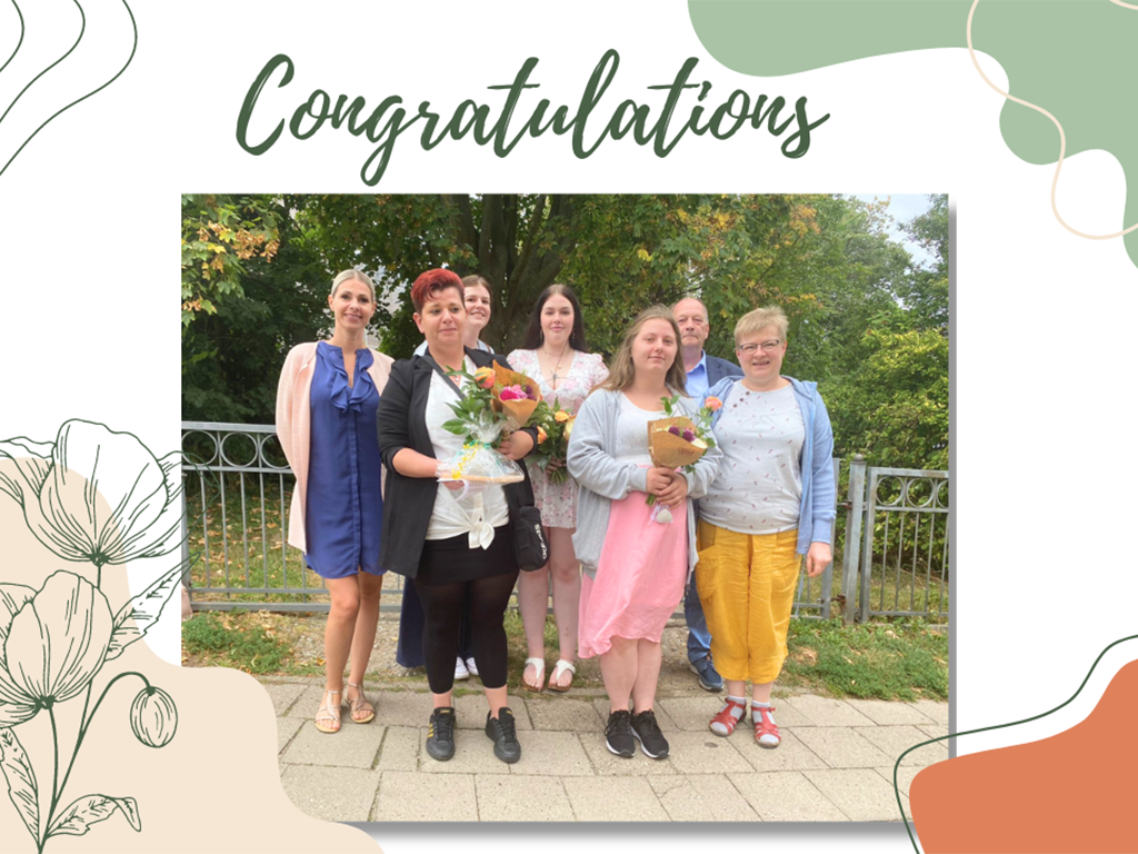 Gruppe von sechs Personen posiert draußen mit Blumensträußen