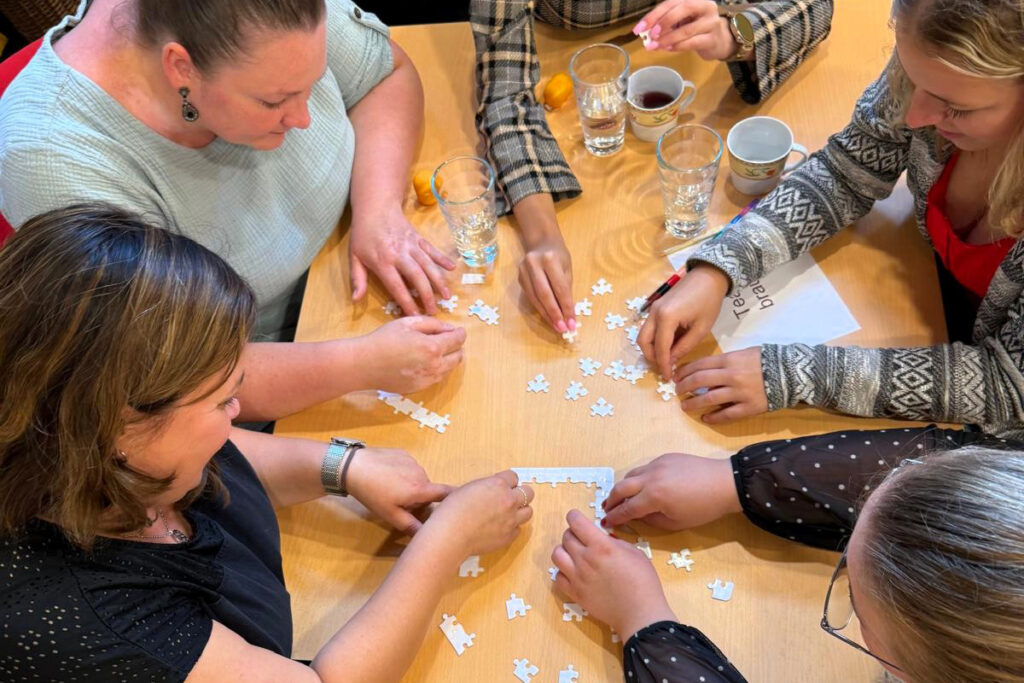 Gruppe von Menschen beim Puzzeln.
