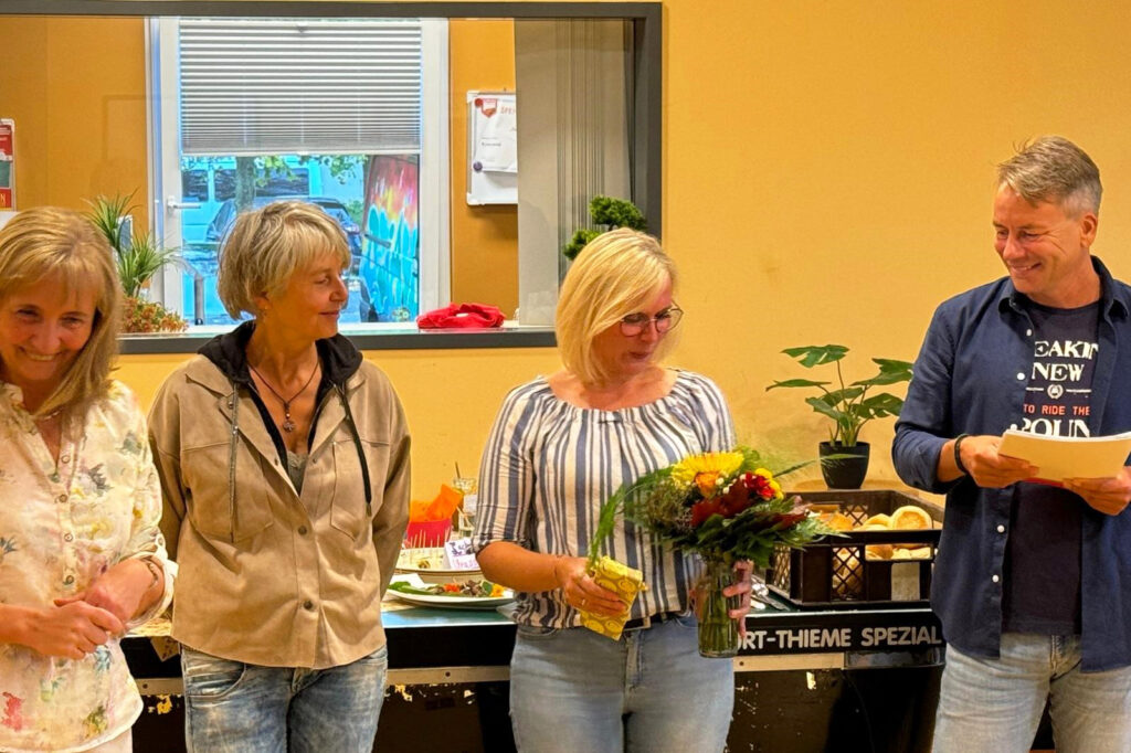 Gruppe von vier Personen in einem Raum mit Fenstern und Pflanzen