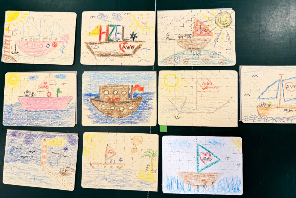 Kinderzeichnungen von Booten mit dem AWO-Logo auf Puzzleteilen