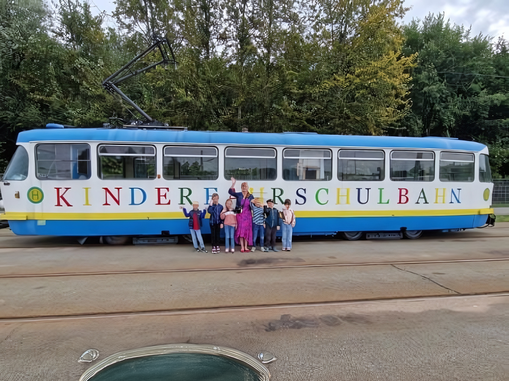 Kinder und Erwachsene vor einer bunten Straßenbahn