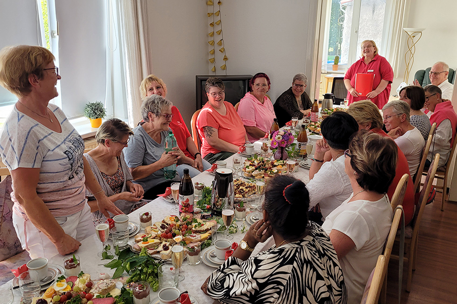 Menschen sitzen an einem gedeckten Tisch in einem hellen Raum.