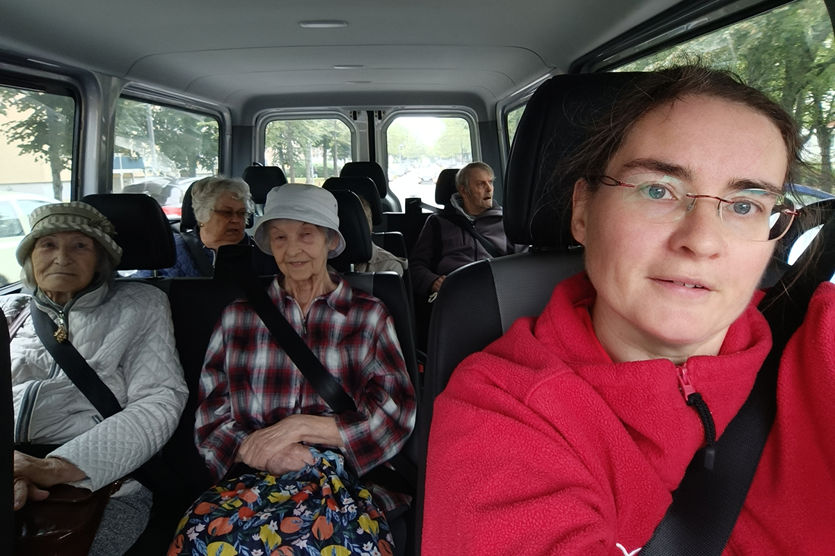 Eine Frau fährt einen Van mit älteren Passagieren.