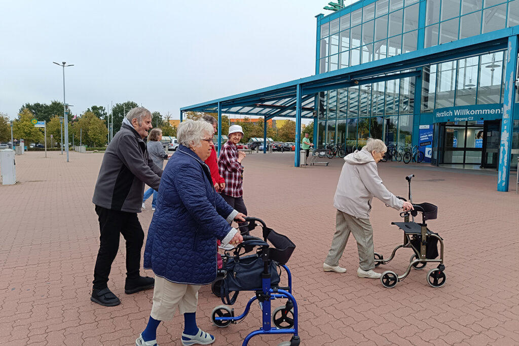 Eine Gruppe &auml;lterer Menschen mit Rollatoren vor einem Einkaufszentrum.