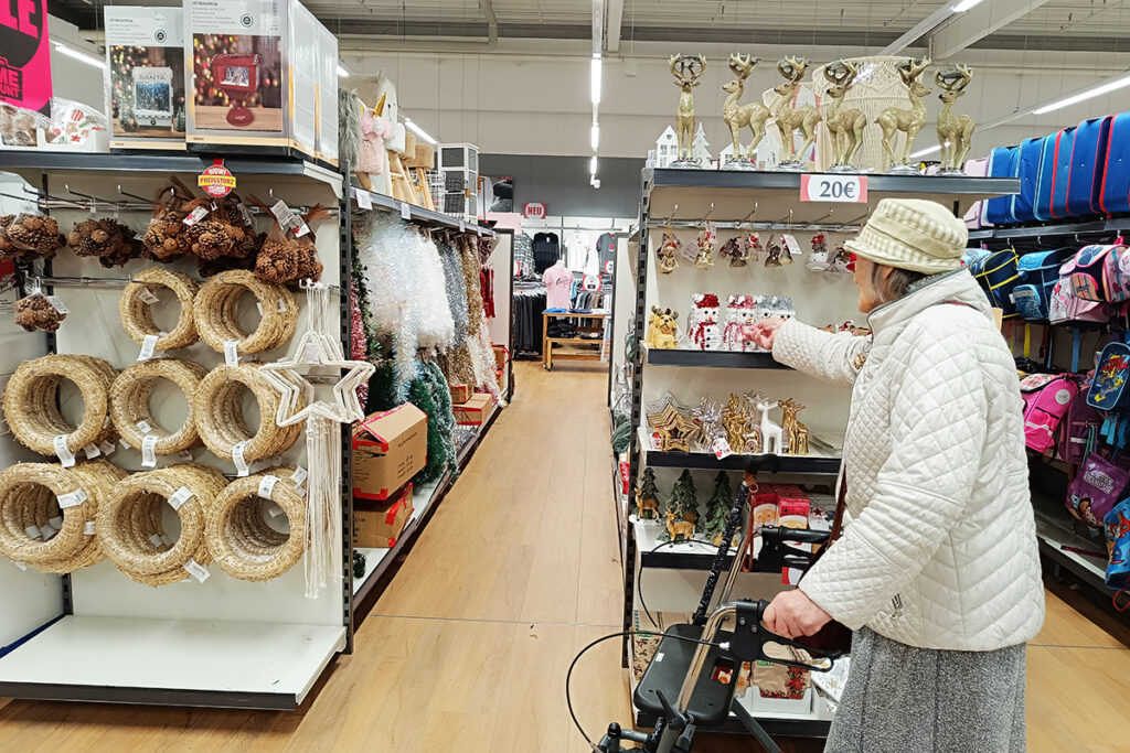 &Auml;ltere Frau beim Einkaufen in einem Gesch&auml;ft, umgeben von Weihnachtsdekorationen.