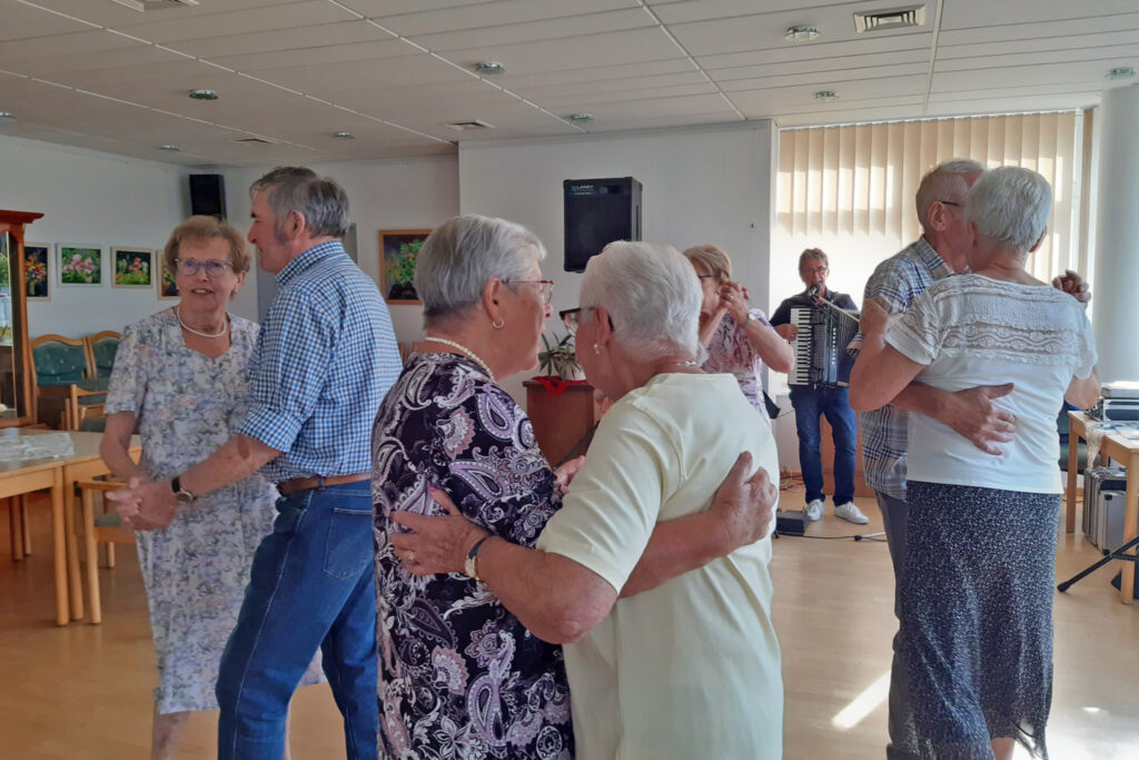 &Auml;ltere Menschen tanzen in einem Raum.