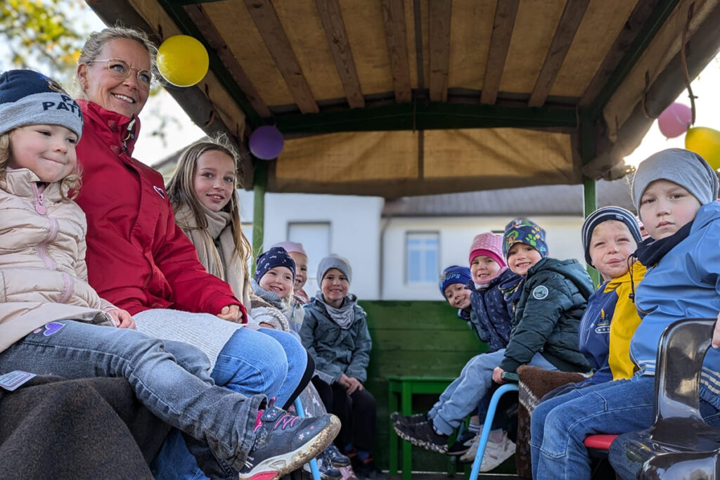 Gruppe von Kindern und einem Erwachsenen in einem &uuml;berdachten Wagen