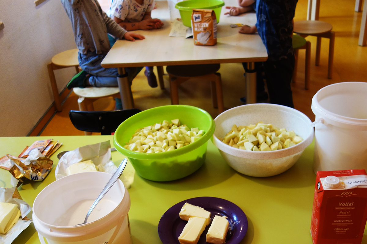 Kinder sitzen an einem Tisch mit Zutaten für das Backen.