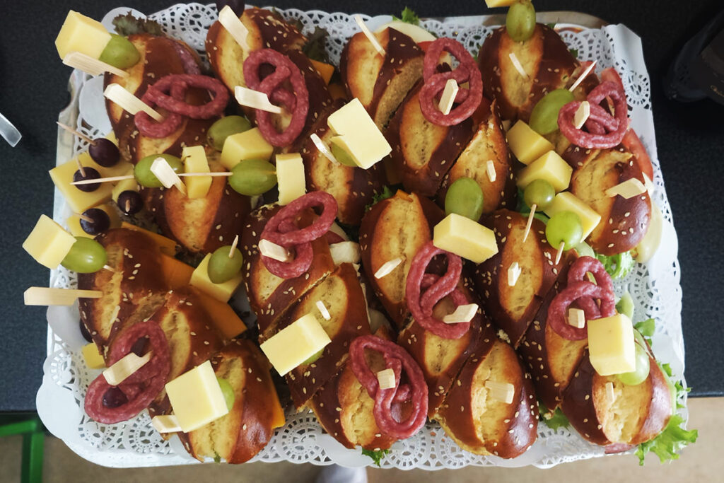 Ein Tablett mit belegten Laugenstangen, dekoriert mit K&auml;sew&uuml;rfeln, Salami und Trauben.