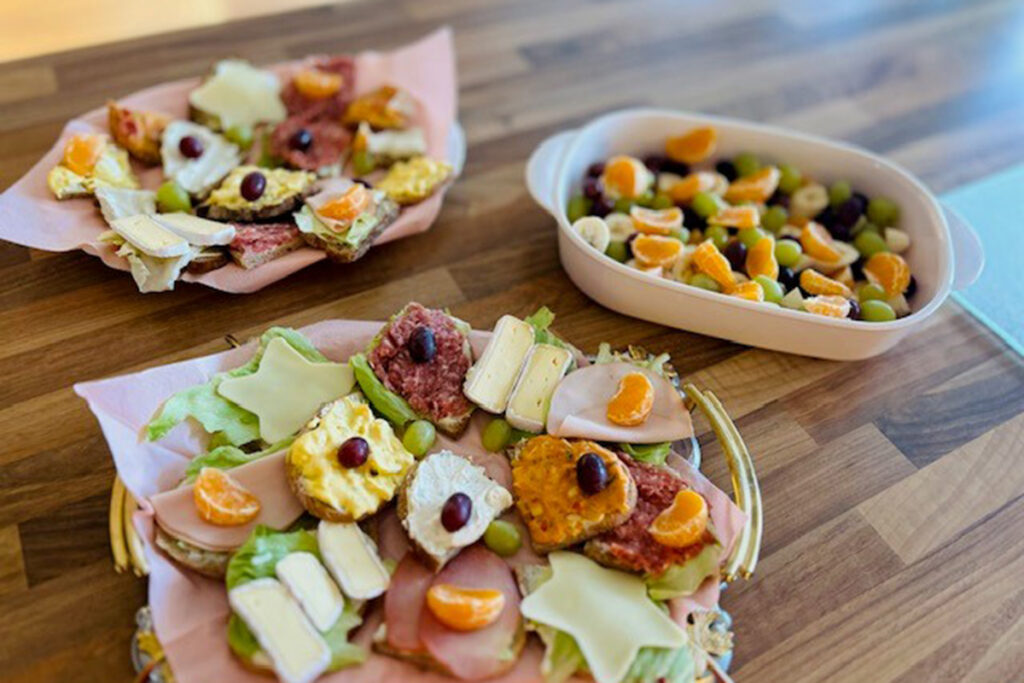 Teller mit belegten Broten und Obstschale