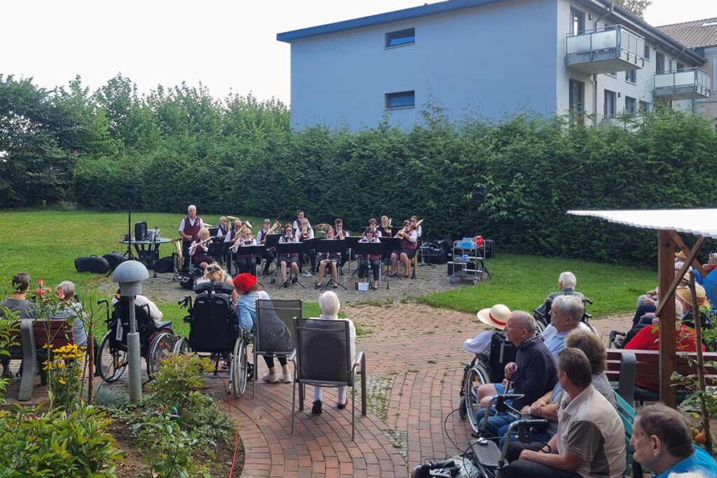 Ein kleines Orchester spielt im Freien vor Senioren.