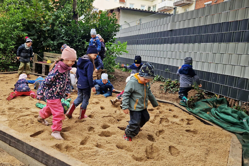 Kinder spielen in einem Sandkasten in einem Au&szlig;enbereich.